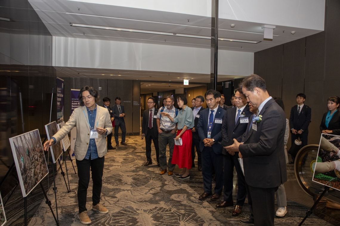 Photographer showing images of restoration project to dignitaries and presenters at the anniversary event in Korea